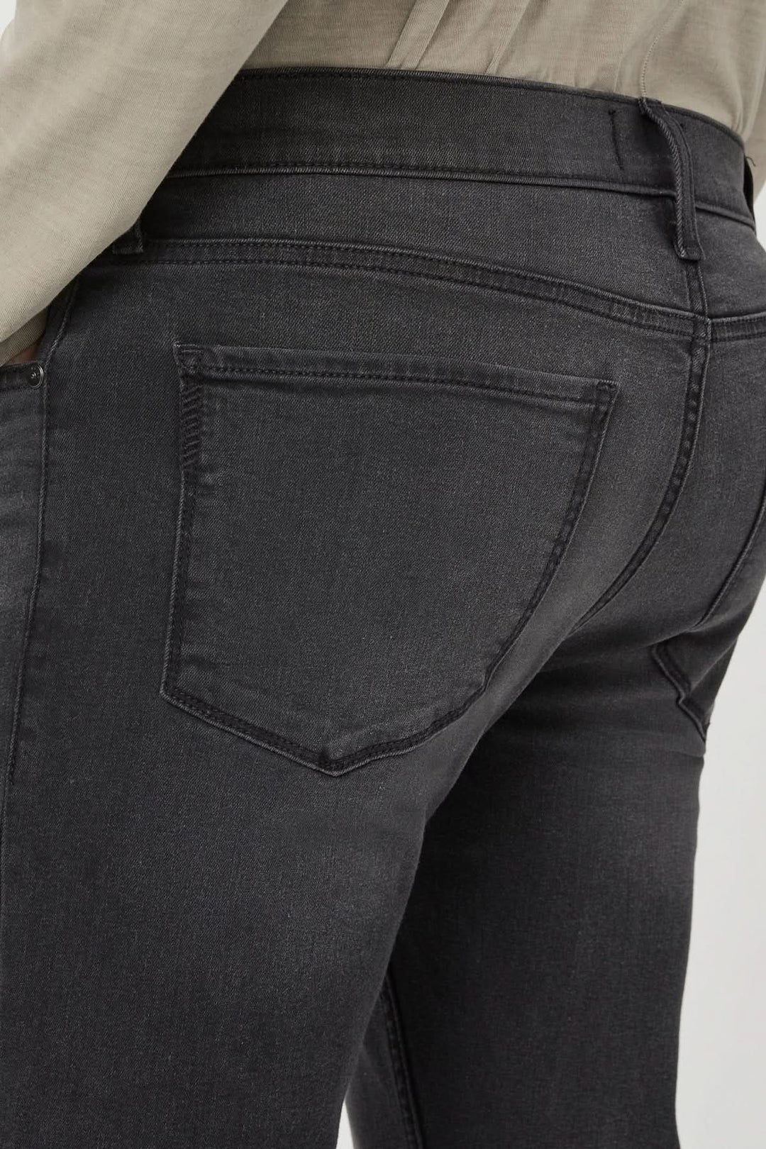 Détail du dos d'un jean slim en denim gris-noir délavé, mettant en avant la coupe ajustée.