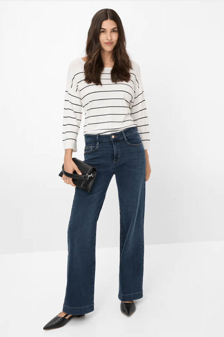 Femme portant un jean délavé évasé avec un pull rayé, accessoirisé d&