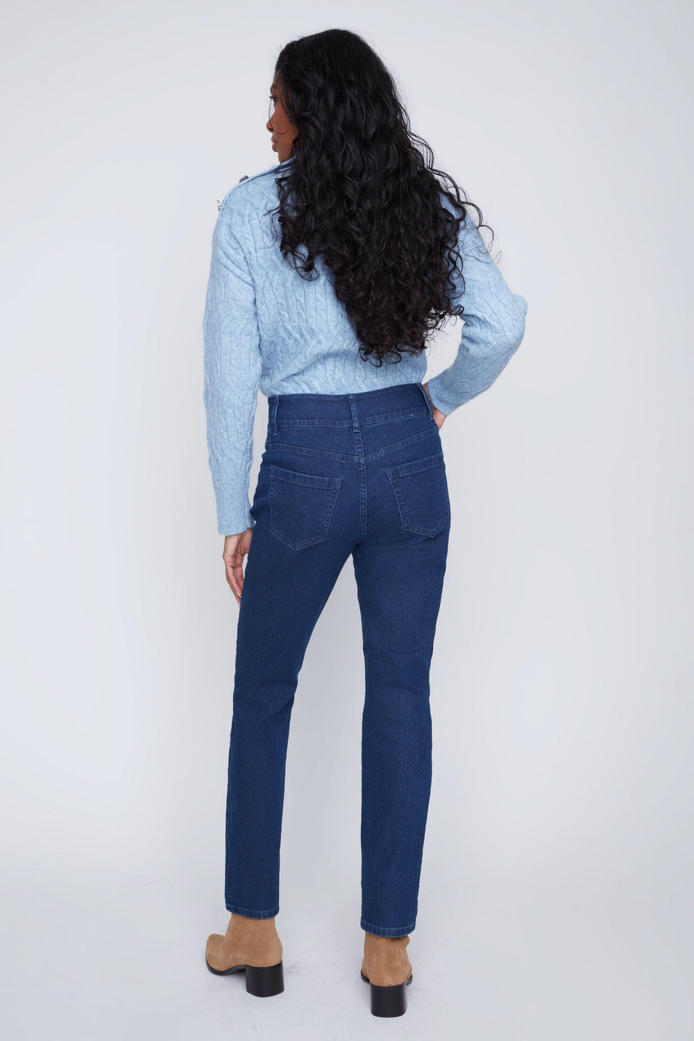 Femme de dos portant un jean taille haute classique avec une chemise bleu clair, mettant en valeur une silhouette élégante.
