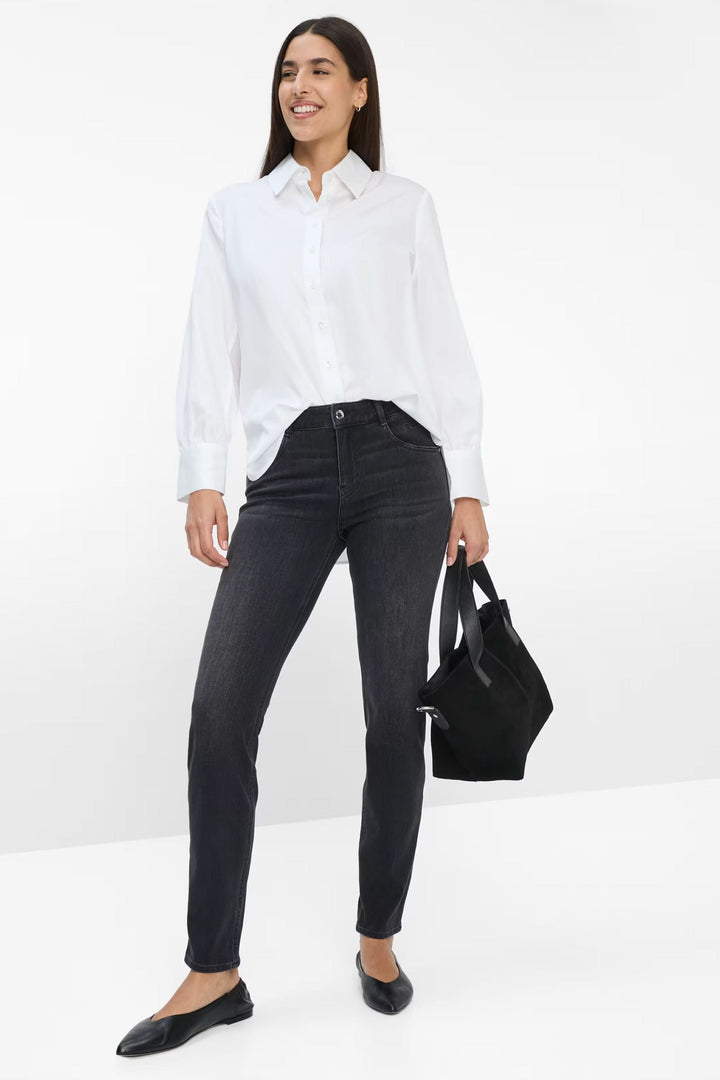 Jeans Shakira coupe ajustée à taille mi-haute en denim extensible, femme portant une chemise blanche et un jean décontracté.