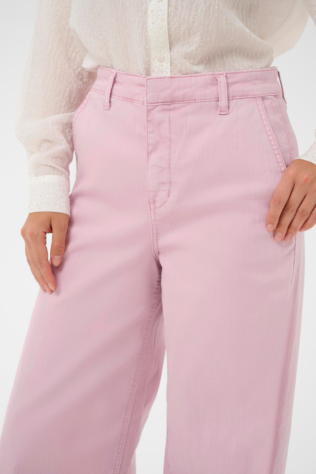 Jeans Visti à jambe large rose, taille régulière, porté avec une blouse blanche, mode moderne et élégante.