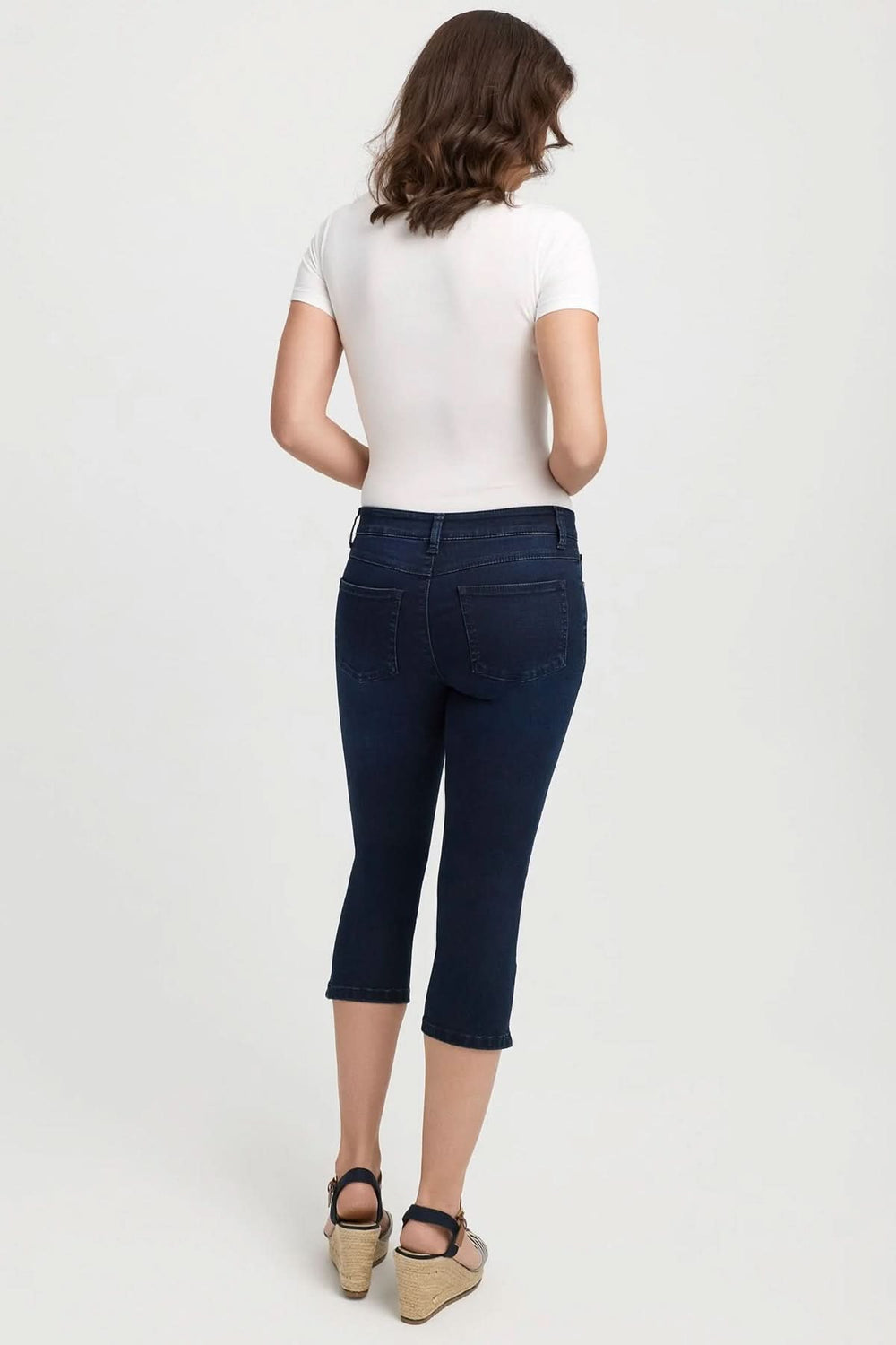 Femme portant des jeans capri ajustés de couleur bleu foncé, vue de dos.