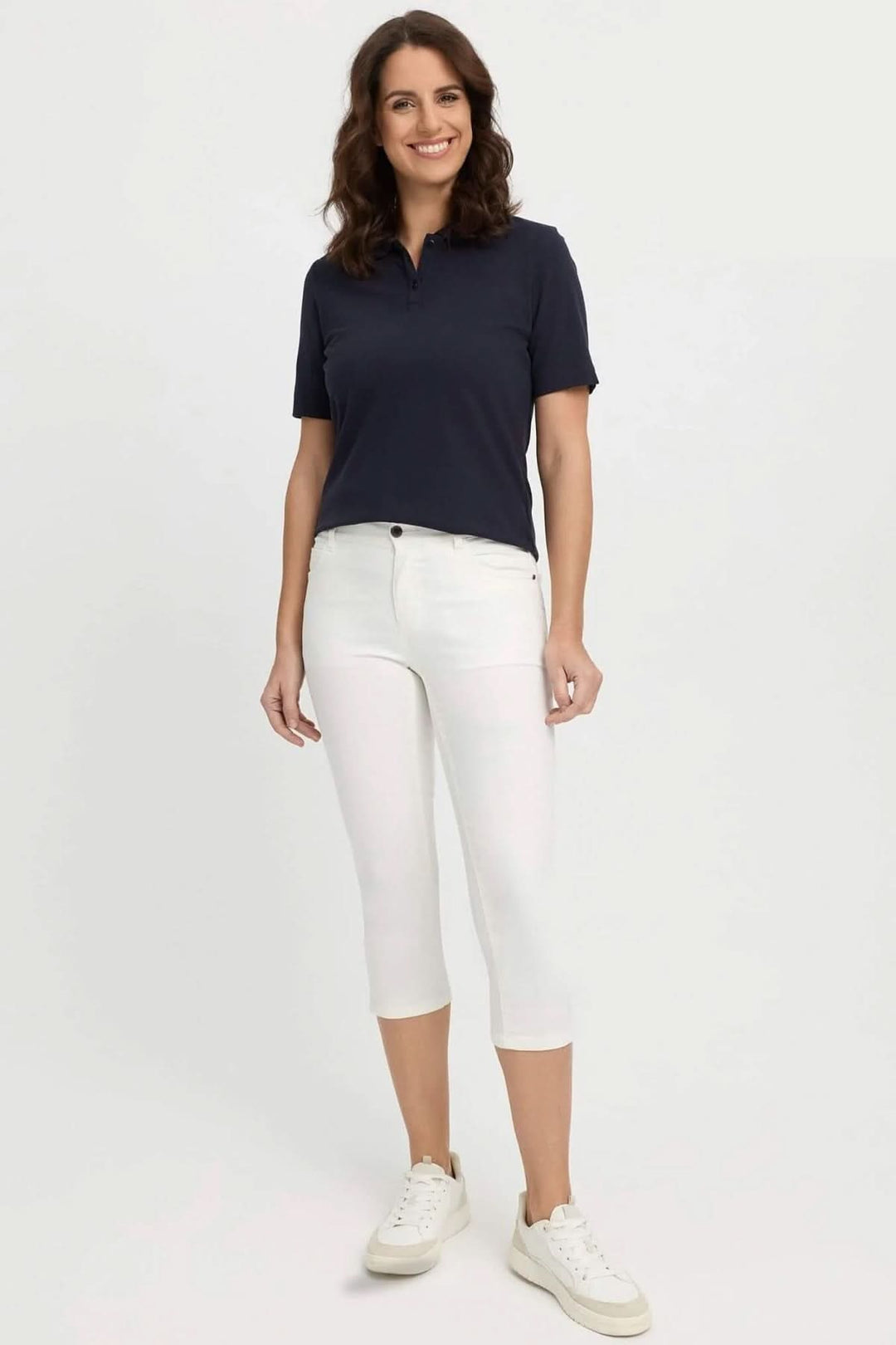 Femme portant un polo noir et des jeans capri blancs, idéale pour un look estival moderne et décontracté.
