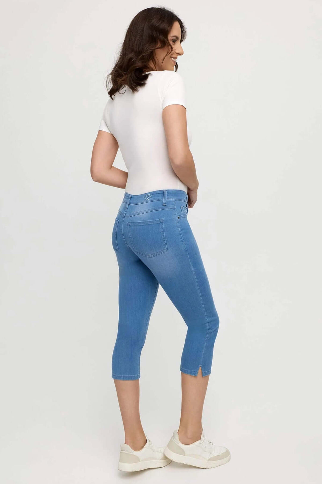 Jeans capri ajustés, longueur 3/4, portés avec un t-shirt blanc, style estival moderne.