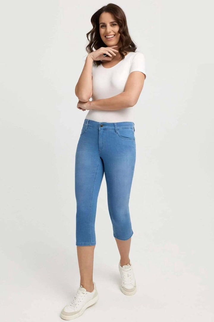 Femme souriante portant des jeans capri ajustés avec un t-shirt blanc, parfaits pour un look estival.