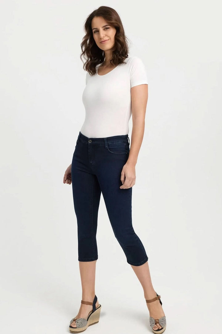 Femme portant un jean capri ajusté, longueur 3/4, avec un t-shirt blanc et sandales, look estival moderne.