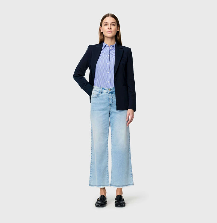 Femme portant un jeans léger Dream wide cropped à jambe large et taille haute avec une veste noire et chemisier bleu.