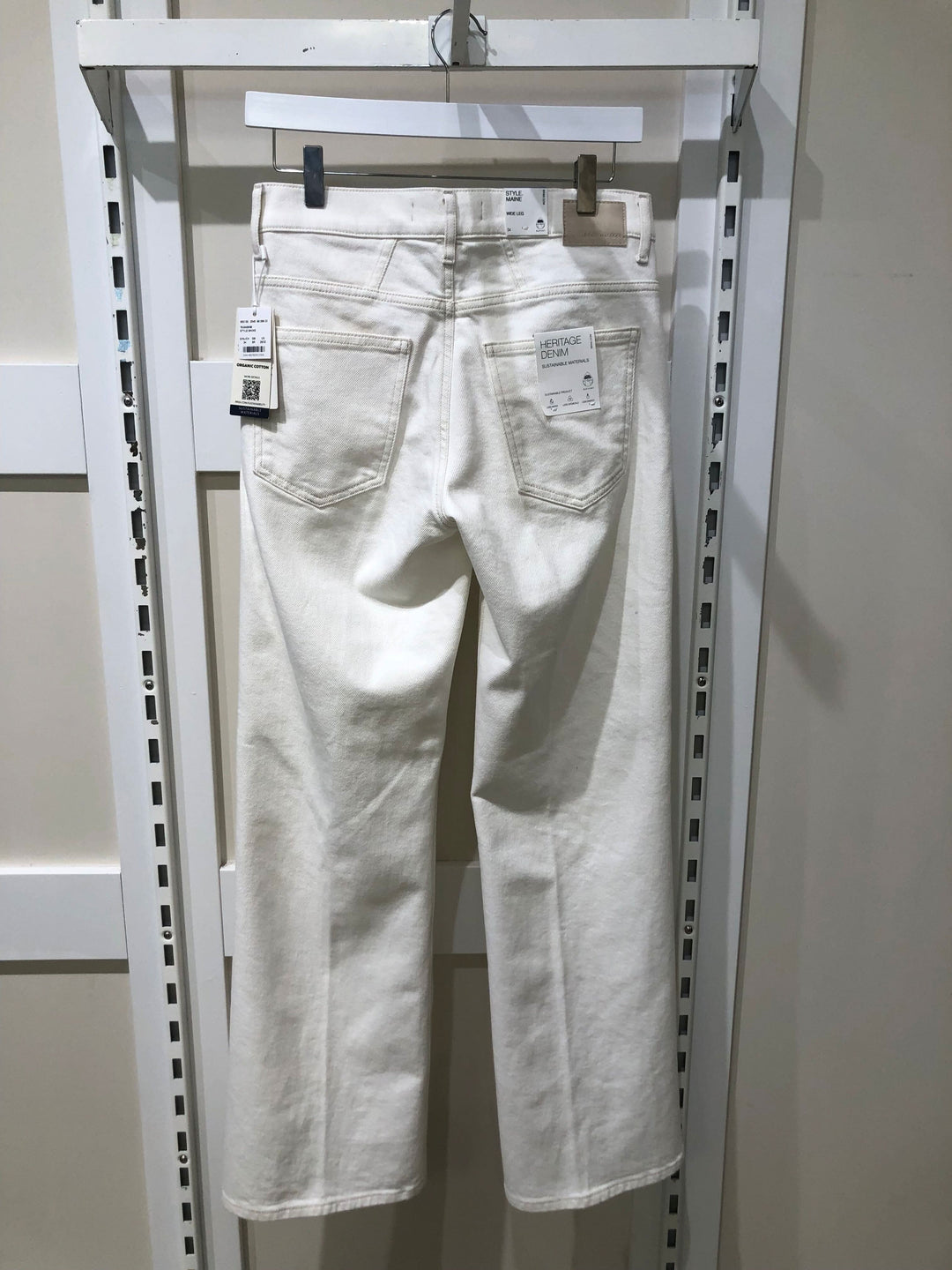 Jeans palazzo blanc MAINE, taille haute, coupe évasée, affichés sur un porte-vêtements en magasin.