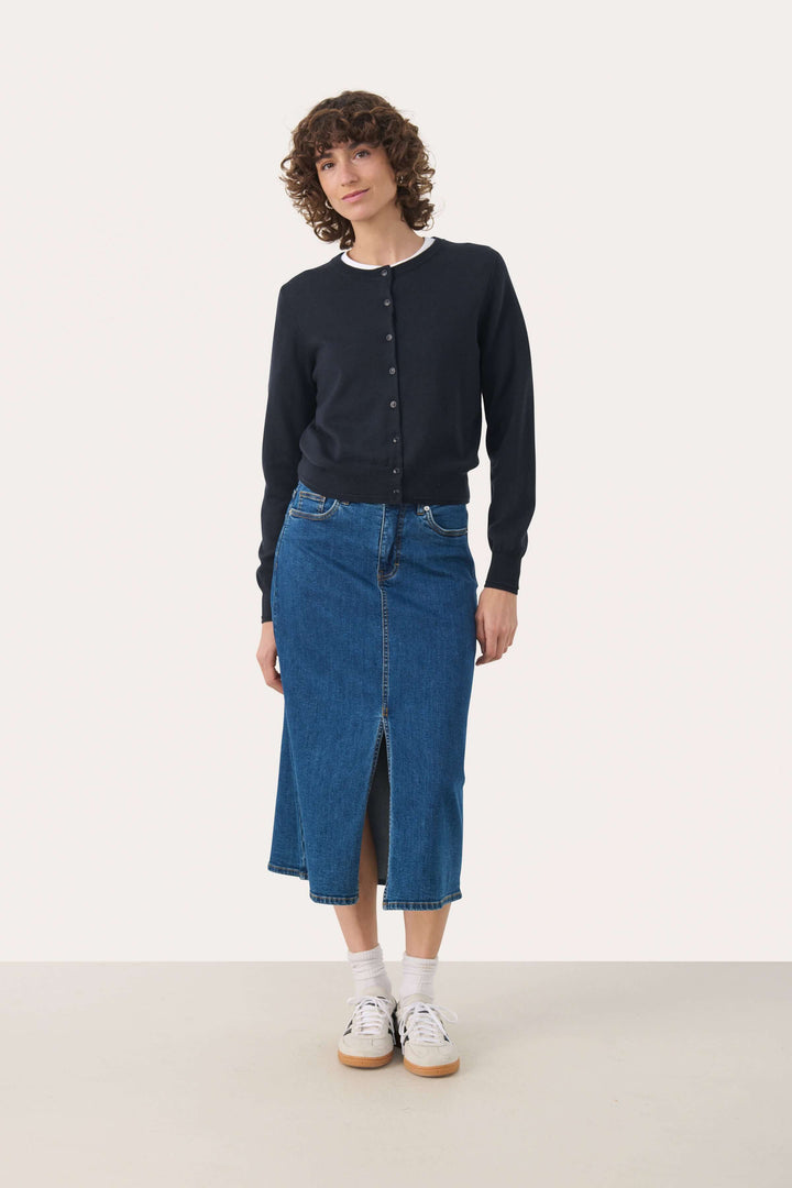 Femme portant la Jupe Dillin en denim avec fente frontale et coupe midi, ajoutant une touche féminine et décontractée.