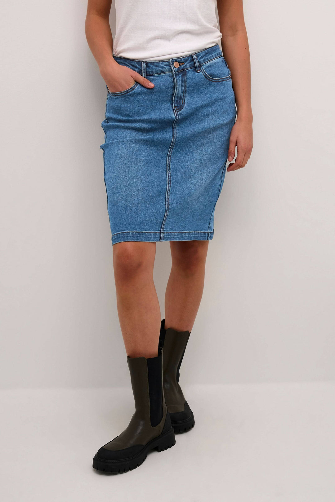 Jupe en jean bleu avec coupe droite, portée avec un t-shirt blanc et des bottes noires, style décontracté.