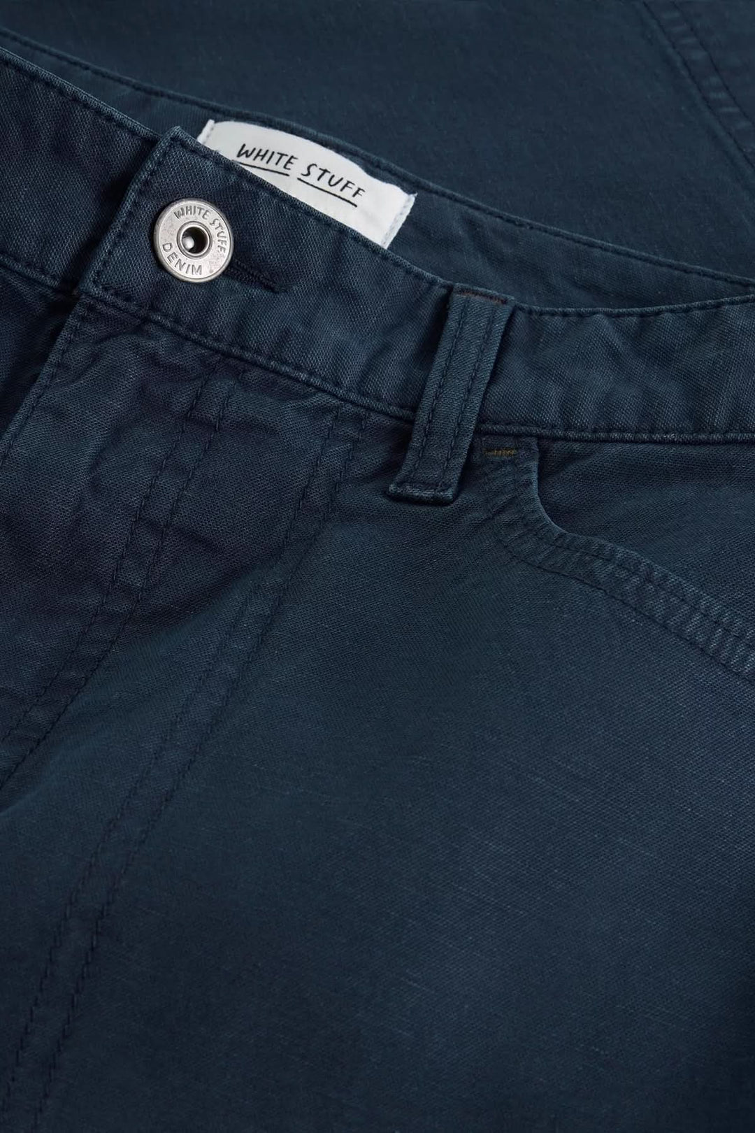 Détail de la ceinture de la Jupe Tia bleu marine avec fermeture par bouton et tissu souple. Jupe Tia idéale pour look urbain chic.