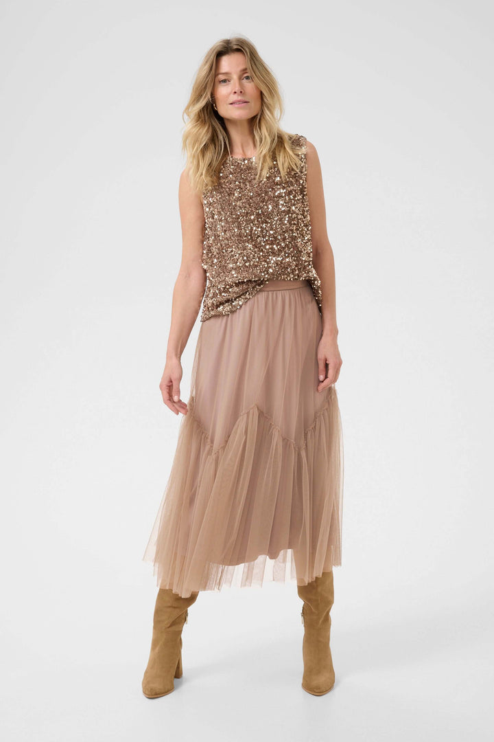 Femme portant une jupe midi en tulle avec un haut à sequins, style romantique et aérien.