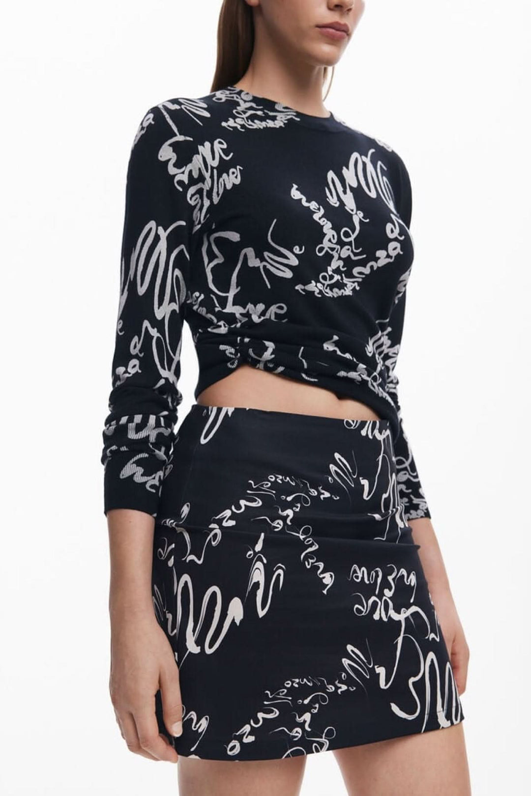 Jupe noire avec imprimé calligraphique blanc, coupe ajustée pour look moderne et artistique.