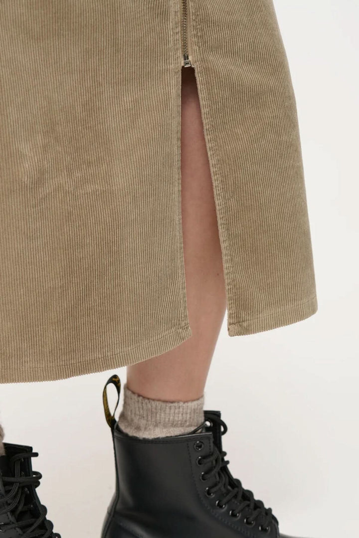 Détail de jupe crayon taille haute en velours côtelé, avec fente et bottes noires.