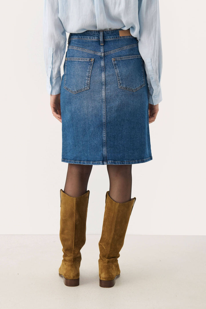 Femme portant une jupe en denim Leja à taille mi-haute, vue arrière, avec des bottes en suède.