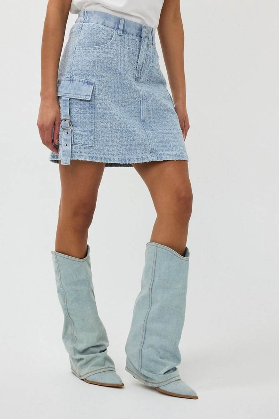Jupe en denim texturé avec poche cargo, coupe trapèze, portée avec des bottes tendance.