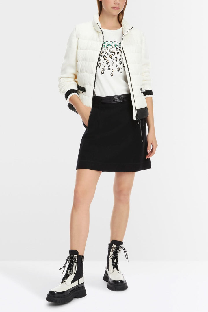Femme portant une mini-jupe en laine tricotée avec une veste légère et des bottes en cuir.