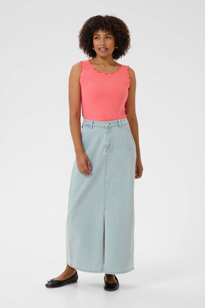 Jupe longue en denim clair avec fente, portée par une femme à la peau claire en haut rose.