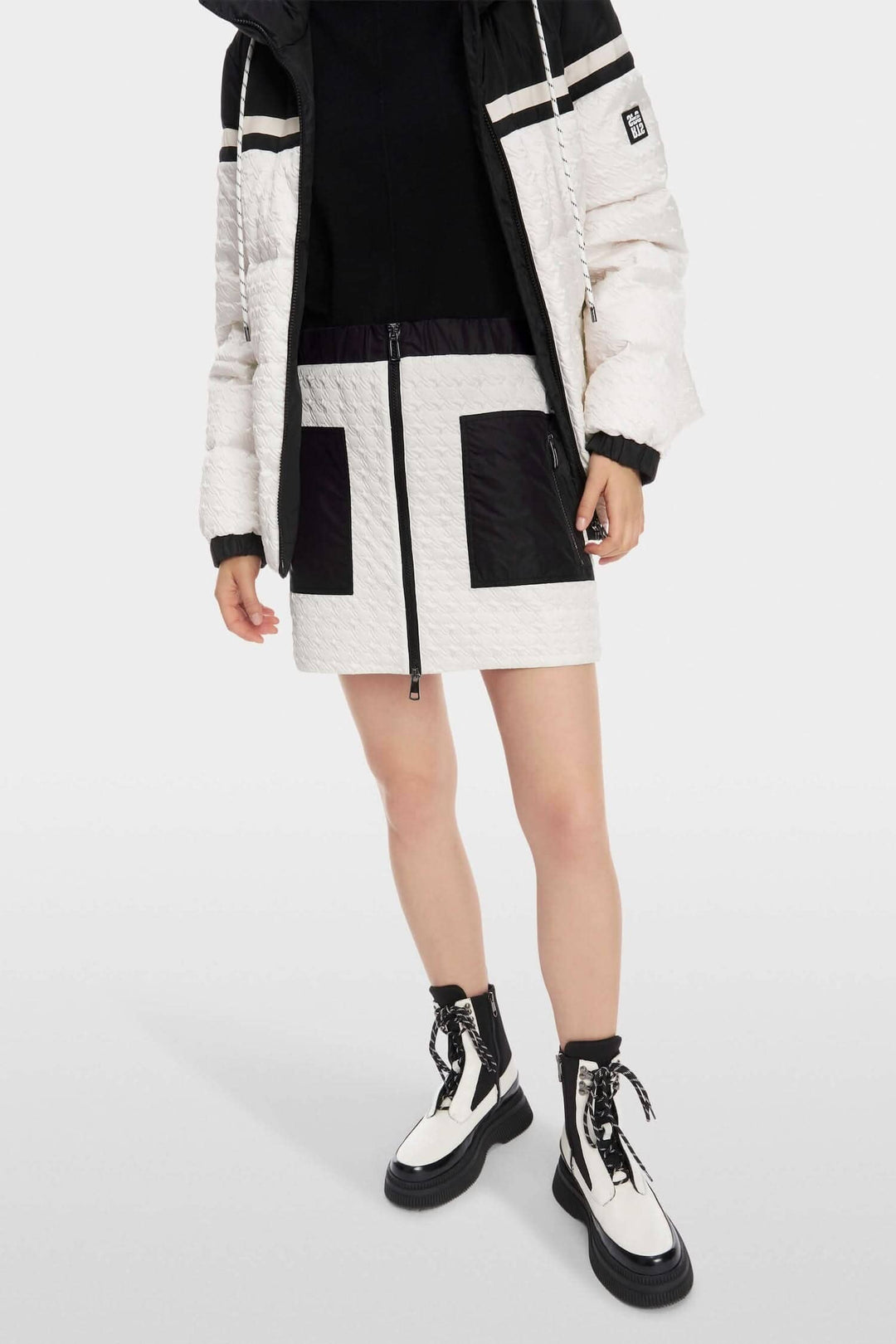 Jupe matelassée sportive avec poches zippées et détails contrastants, associée à une veste élégante.