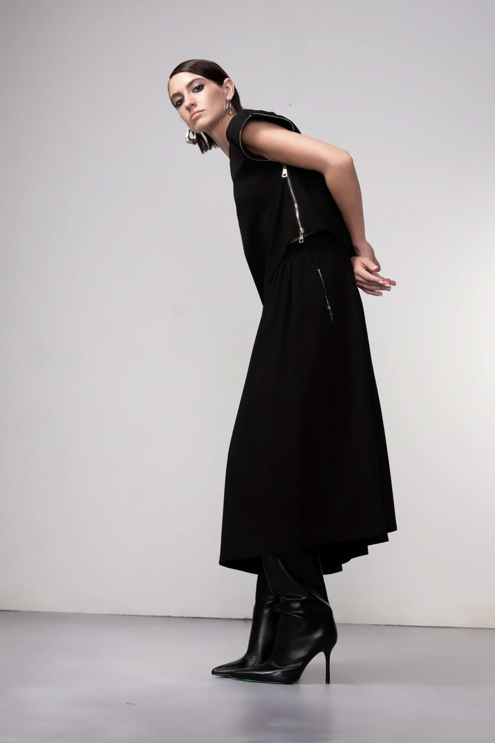 Jupe midi coupe fluide noire portée avec élégance, silhouette asymétrique, style contemporain et polyvalent.