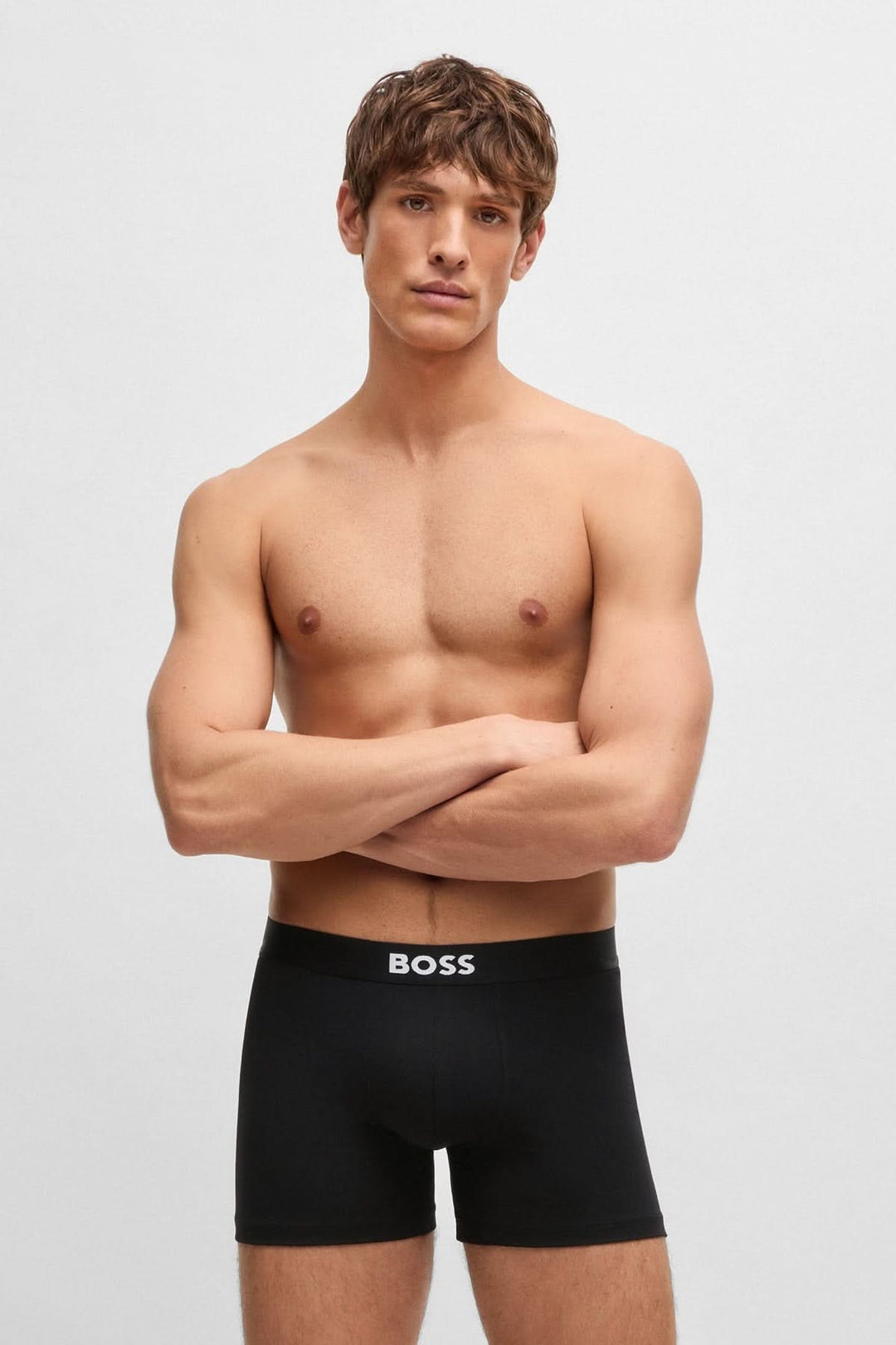 Homme portant boxers noirs avec ceinture logo BOSS, affichant confort et style moderne.