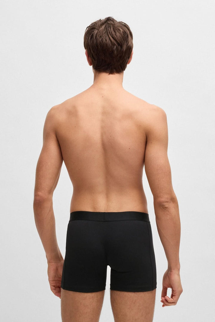 Homme vu de dos portant un boxer noir à ceinture logo, illustrant confort et style moderne.