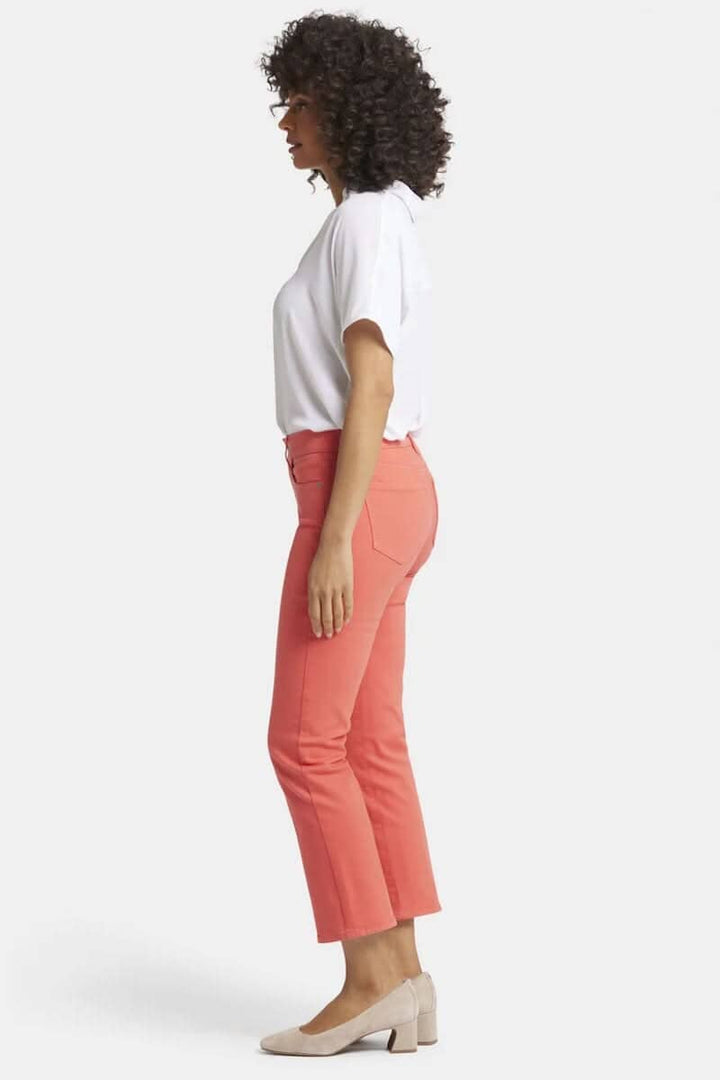 Pantalon Marilyn en corail, coupe classique, porté avec un haut blanc, en vue de profil.