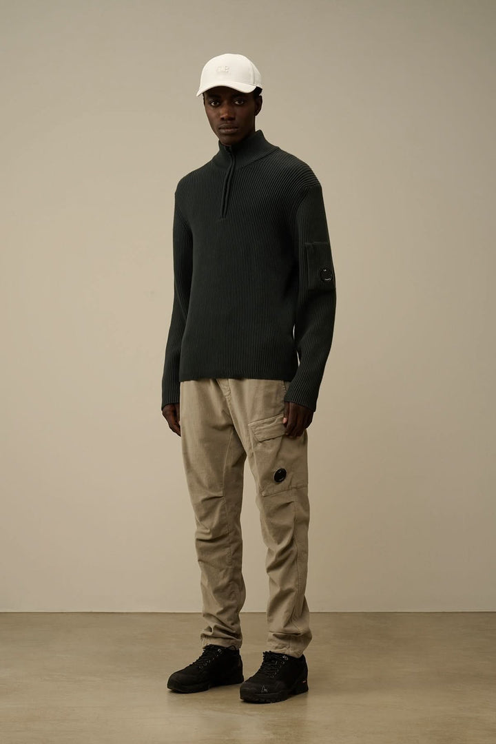Homme portant un tricot demi-zip en côtes anglaises et pantalon cargo beige, style décontracté.