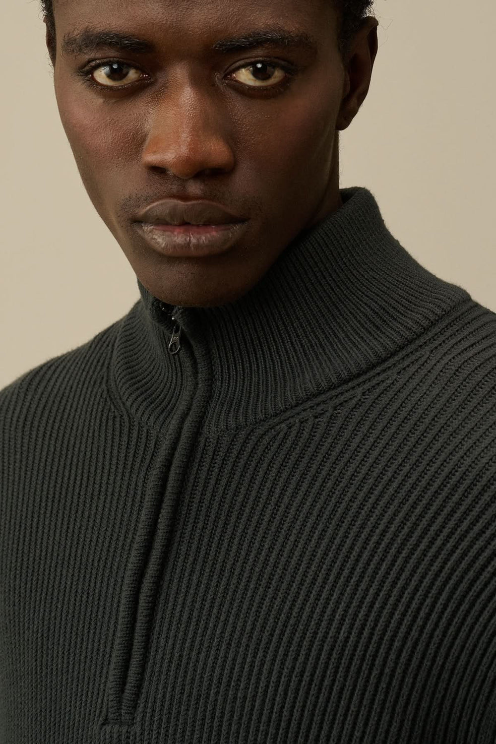 Homme portant un tricot demi-zip en côtes anglaises, couleur gris foncé, avec encolure côtelée.