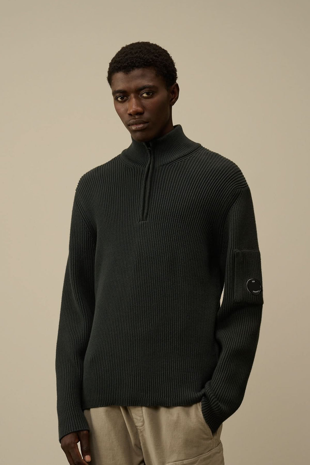Maille côtelée noire avec fermeture semi-zippée portée par un homme, style décontracté.