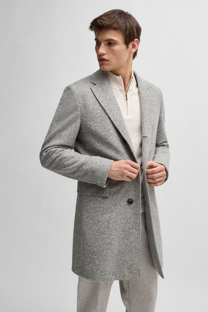 Manteau à chevrons gris pour homme, coupe ajustée, avec fermeture amovible, style élégant et moderne.