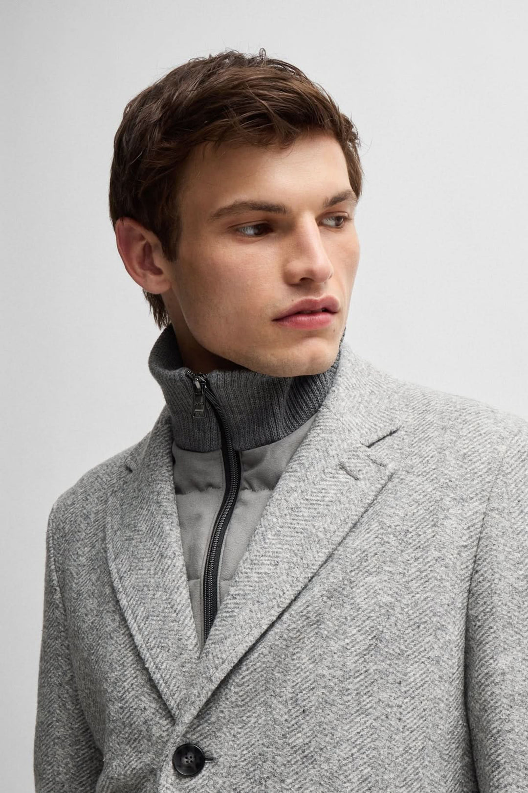 Homme portant un manteau à chevrons gris avec une fermeture éclair amovible, détail sur le col.