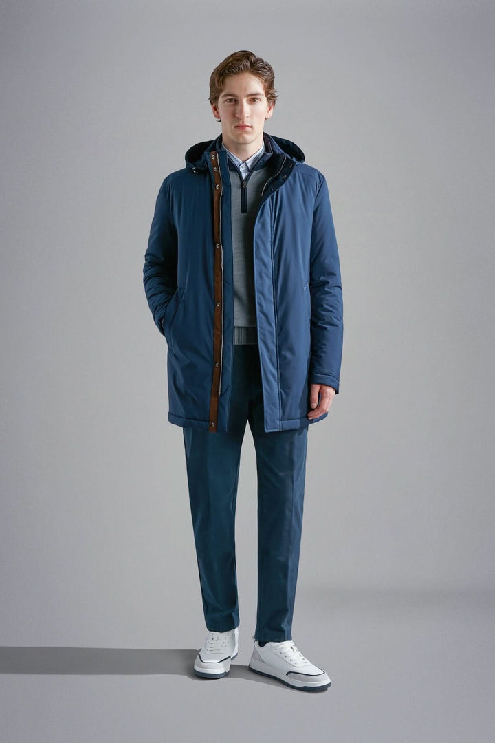 Manteau d'hiver Primaloft bleu marine avec capuche, porté par un homme debout, style moderne et élégant.