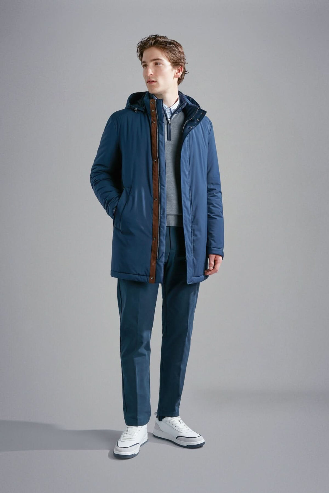 Homme portant un manteau d'hiver Primaloft bleu marine avec capuche, look élégant et confortable.