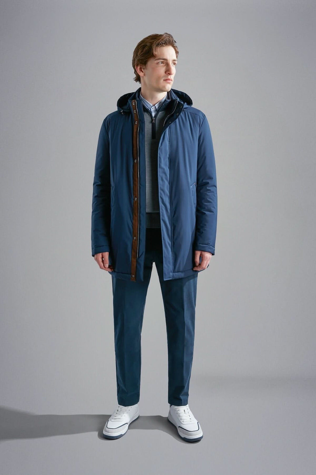 Homme portant un manteau d'hiver bleu marine avec capuche et pantalon assorti, style décontracté.