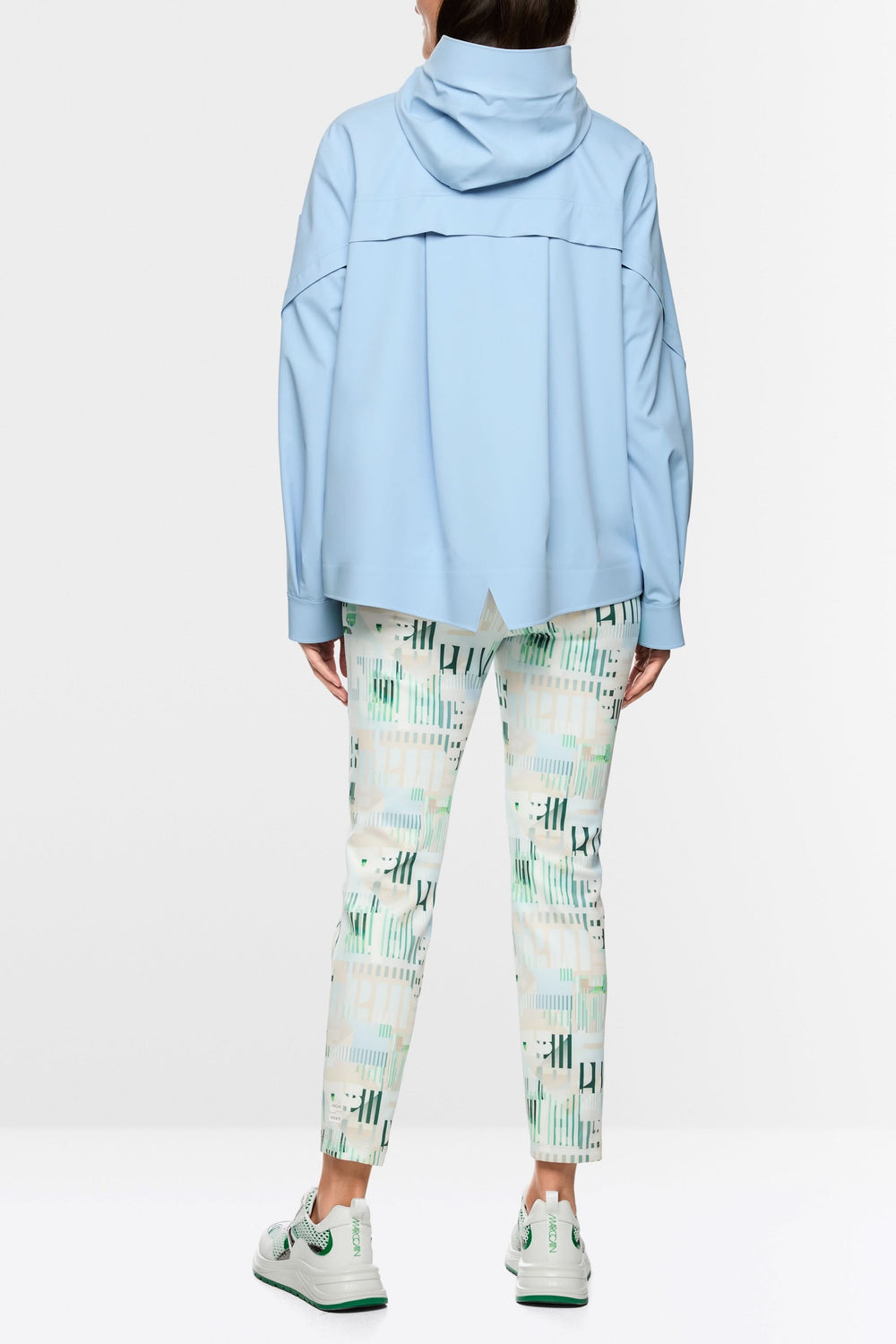 Vue arrière du manteau d'extérieur léger avec capuche bleu, mannequin portant pantalon imprimé et baskets blanches.