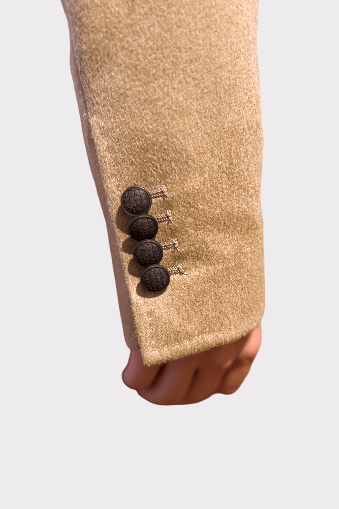 Manche d'un manteau en poil de chameau présentant des boutons élégants en relief.