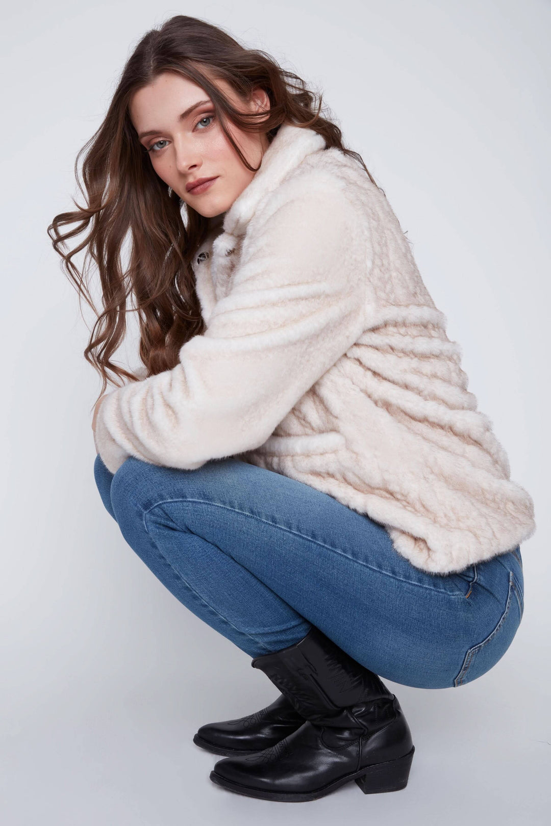 Manteau en fausse fourrure beige porté sur un pantalon en jean, style chic et décontracté, parfait pour la mi-saison.