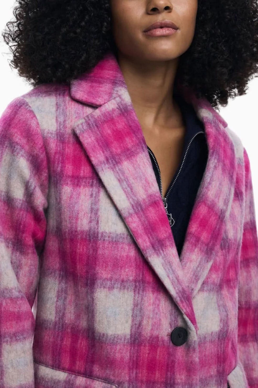 Manteau long à carreaux rose avec col à revers, porté par un mannequin, style moderne et élégance pour la mi-saison.