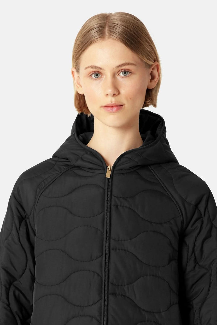 Modèle portant un manteau matelassé long à capuchon noir avec motifs ondulés, décris moi le produit en français.