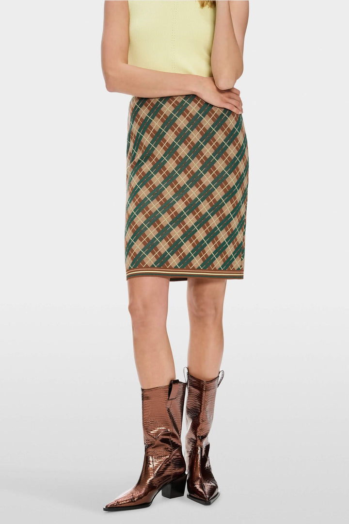 Mini-jupe à carreaux argyle avec ceinture élastiquée, portée avec des bottes brillantes.