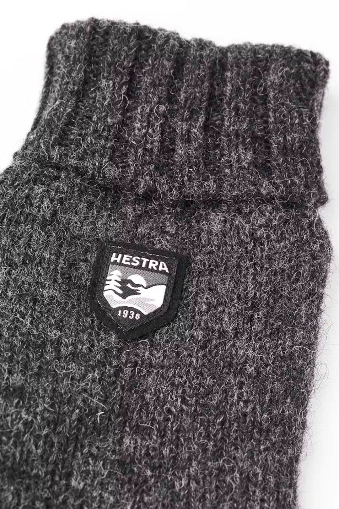 Mitaine en laine Hestra, tricotée gris, avec revers côtelé et logo, idéale pour l'automne et l'hiver.