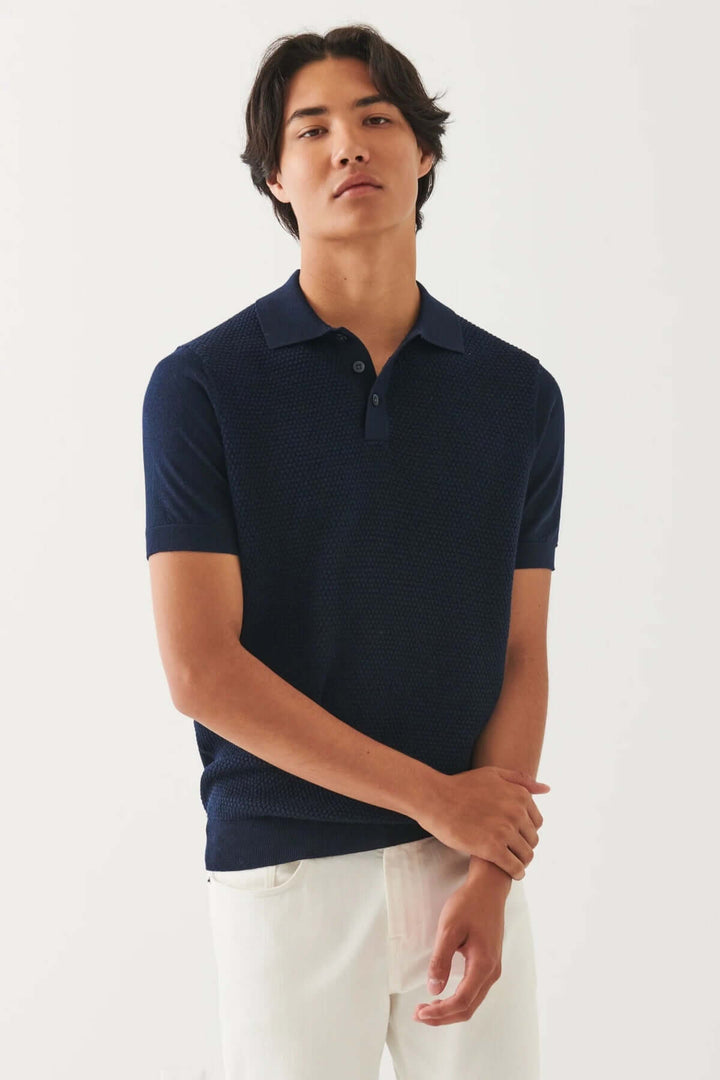 Homme en polo bleu marine ajusté, style décontracté, manches courtes, sur fond clair.