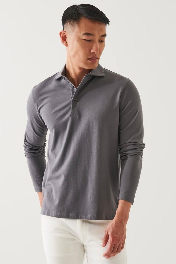 Polo en coton stretch à manches longues, col surpiqué, porté de manière décontractée ou habillée.