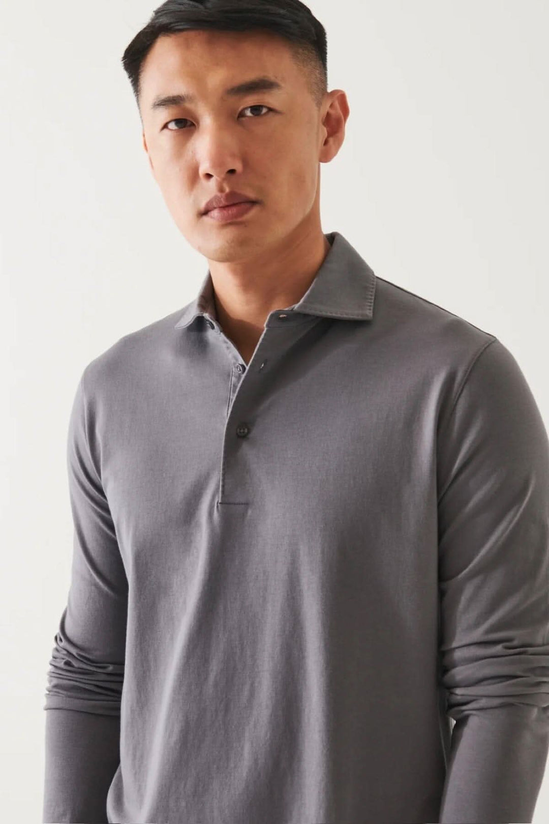 Polo à manches longues en coton pima extensible gris, col surpiqué, porté par un mannequin.