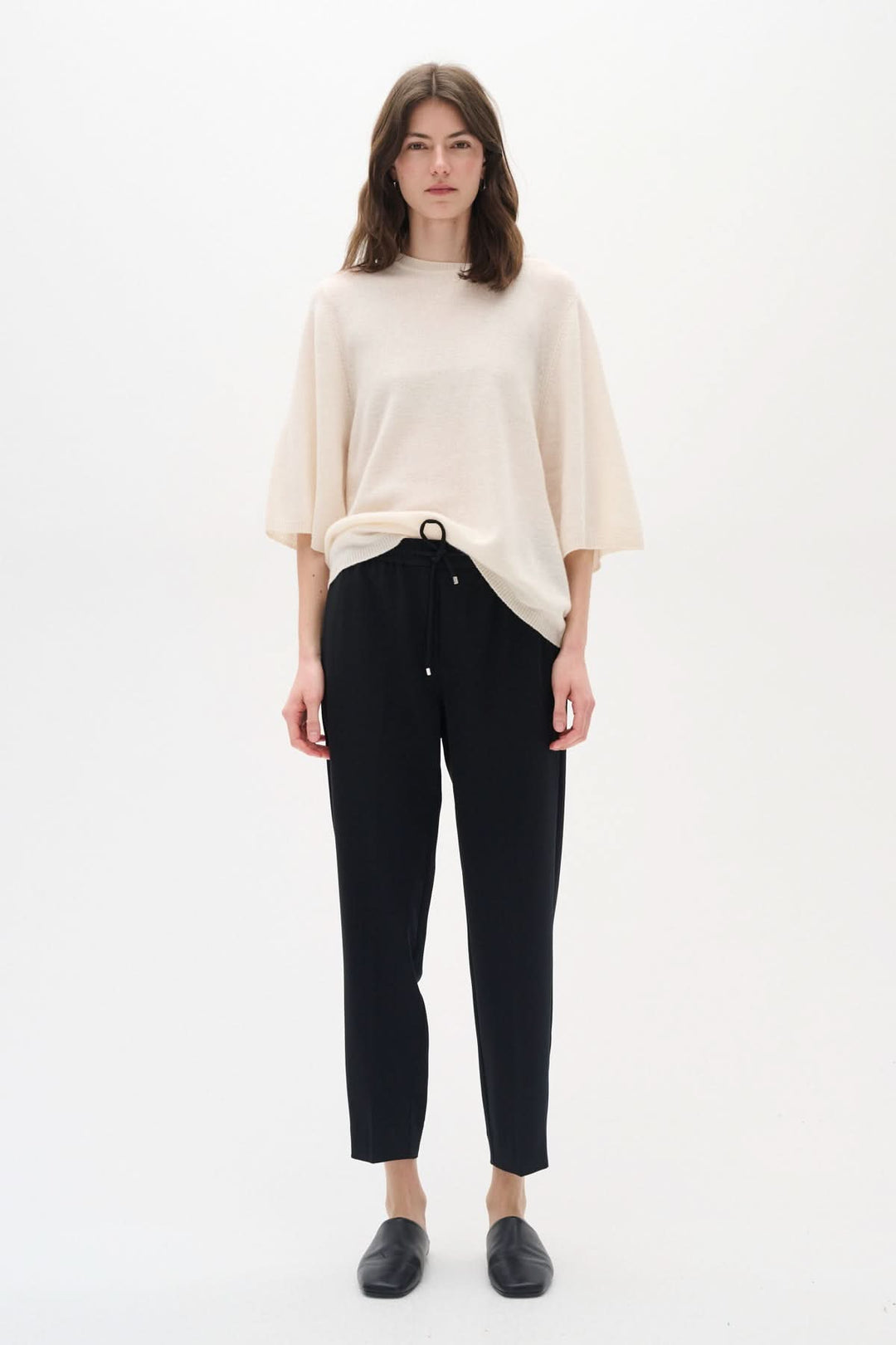 Femme portant un pantalon Adian noir inspiré du jogger, associé à un haut beige, dans un look décontracté.
