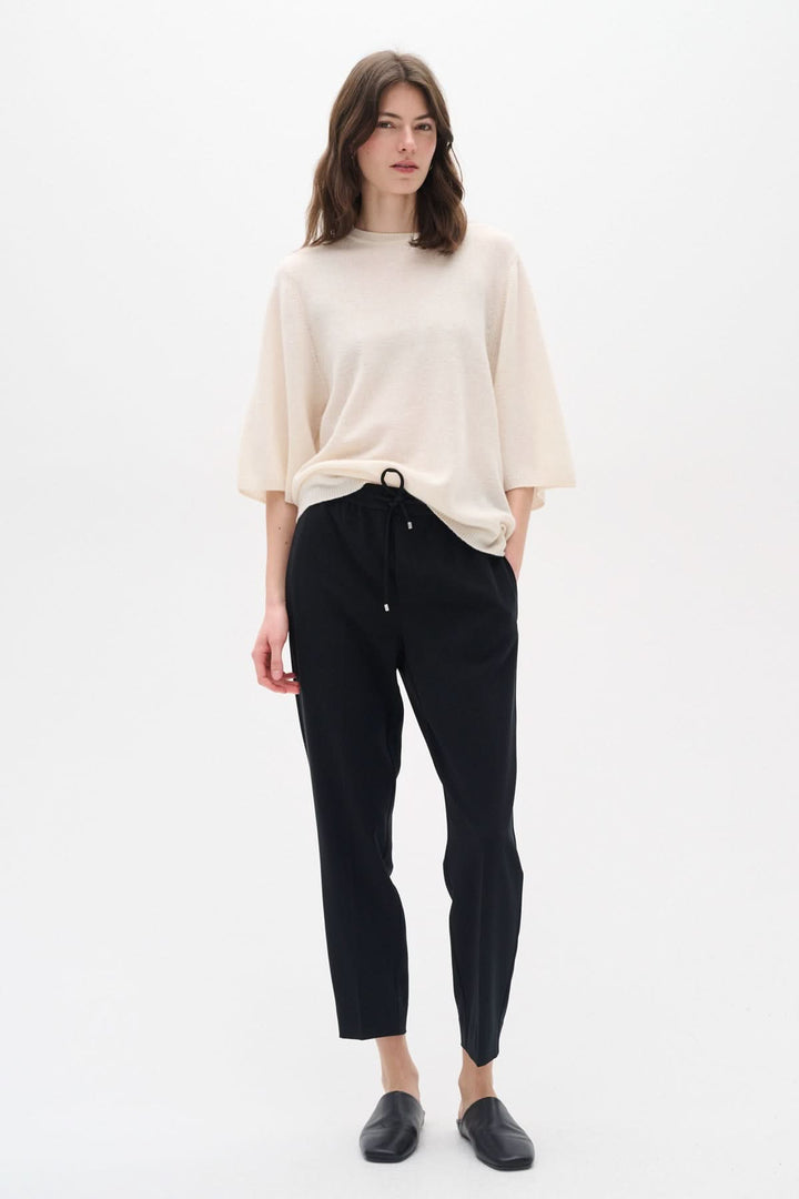 Femme portant le pantalon Adian avec un haut beige, offrant un look chic et décontracté.