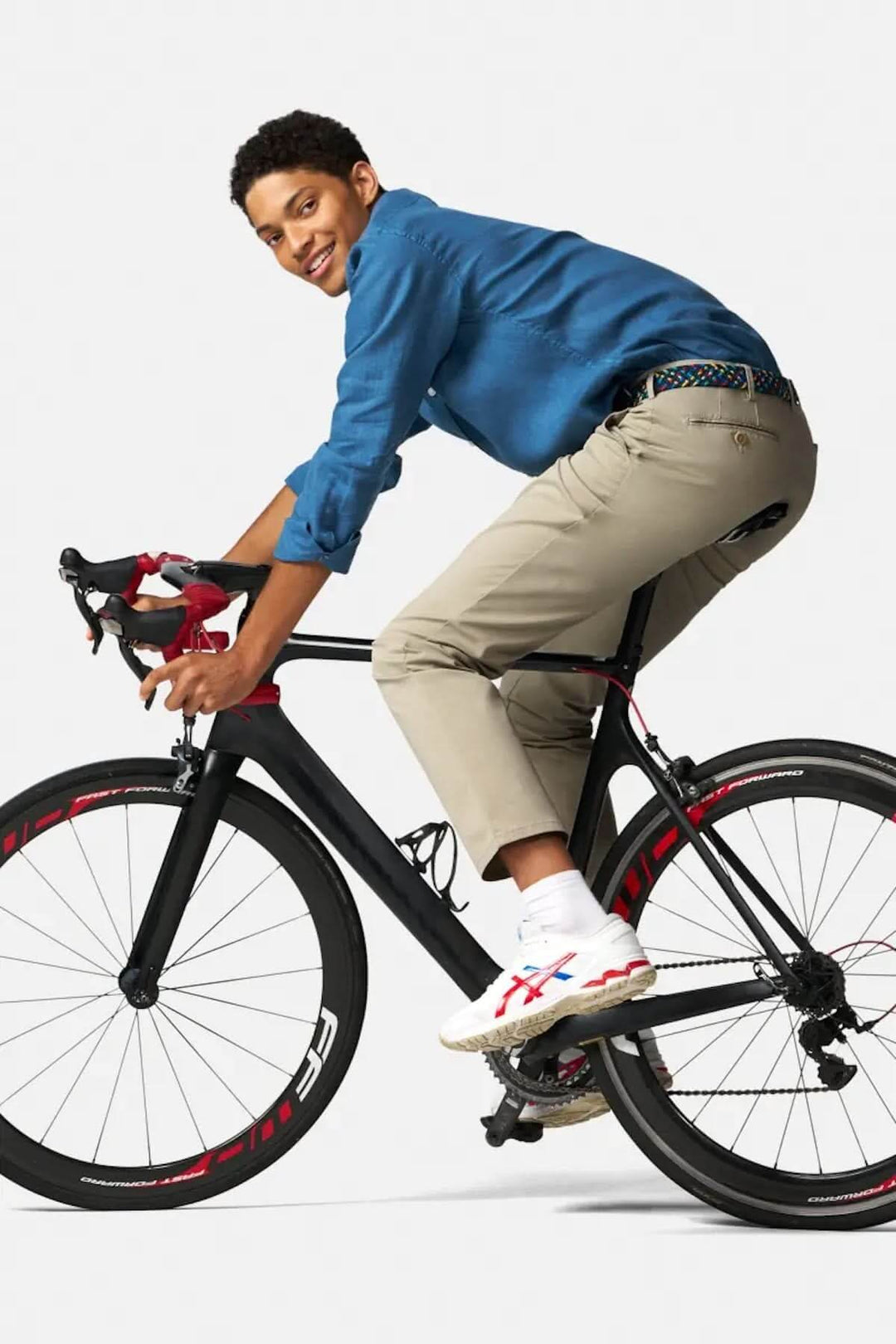 Jeune homme en pantalon Bonn, vêtu d'une chemise bleue, montant un vélo, illustrant style et confort.