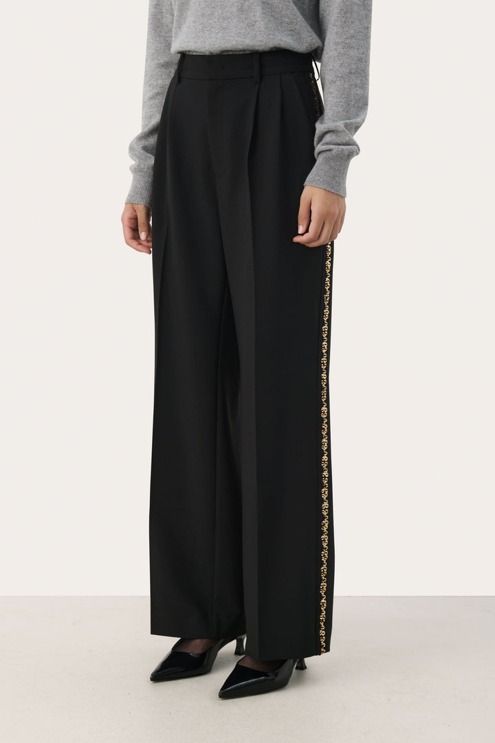 Pantalon noir large avec bande brodée dorée sur les côtés, taille haute, élégant et confortable.