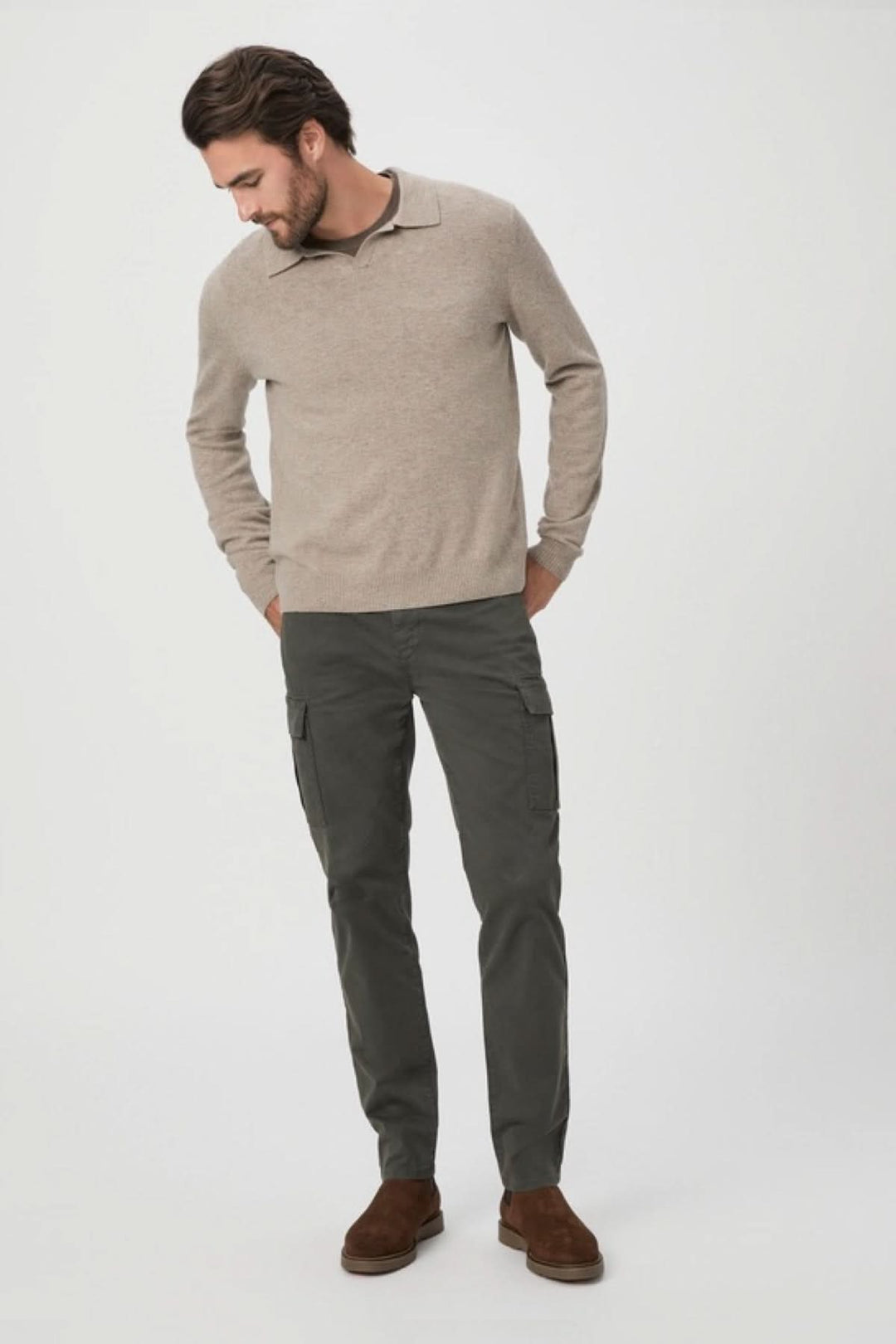 Homme portant un pull beige et un pantalon cargo noir, style décontracté et élégant.
